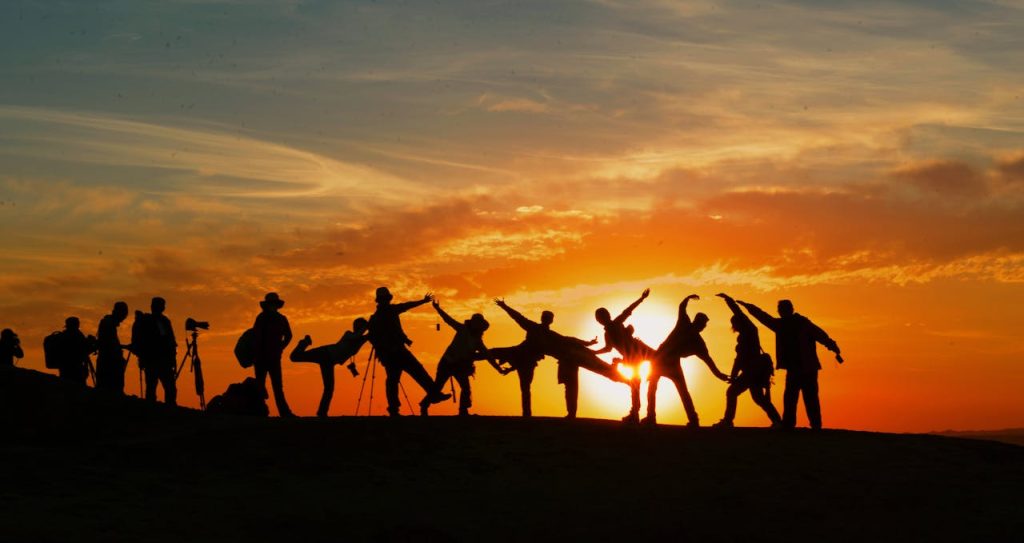 pexels-photo-207896 Group of people silhouetted against a vibrant sunset, showcasing unity and joy.